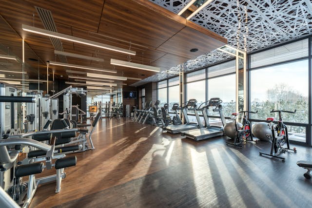 Fitness gym with people working out, lifting weights, and using exercise machines to stay fit and healthy