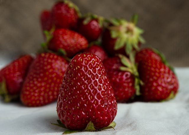 A pile of fresh strawberries arranged on a white cloth