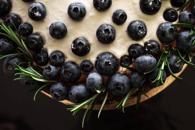 A wellness cake topped with blueberries and rosemary